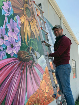 Ehren Knapp next to his wall mural